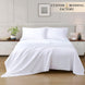 White bedding set on a bed in a bedroom with 'Custom Bedding Factory' branding.